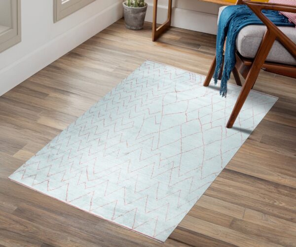 Pale blue zigzag rug on wood planks next to a wooden chair draped with a bright blue throw.