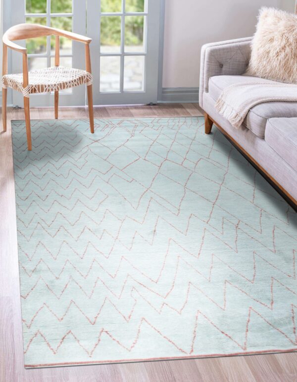 Pale blue rug featuring thin orange geometric lines on wood flooring, next to a chair and gray sofa.