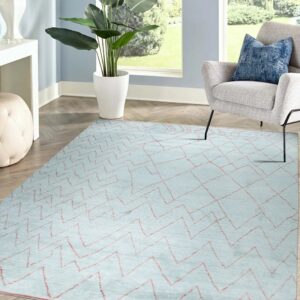 Pale blue geometric rug with coral lines anchors a seating area with a gray chair and potted plant.