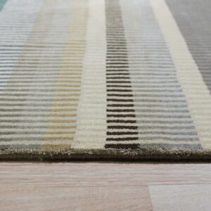 Textured, medium pile rug with horizontal bars forming teal, cream, gray, and brown vertical stripes on wood flooring.