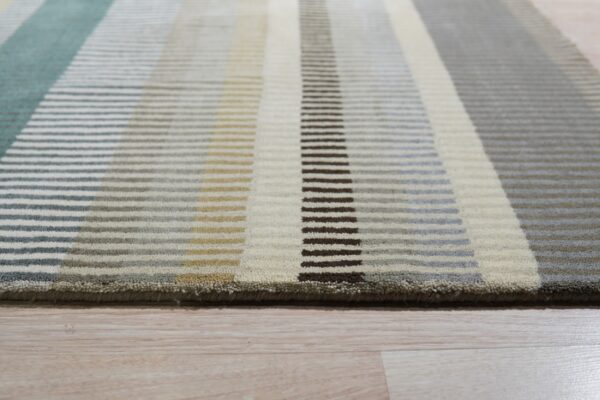 Textured, medium pile rug with horizontal bars forming teal, cream, gray, and brown vertical stripes on wood flooring.