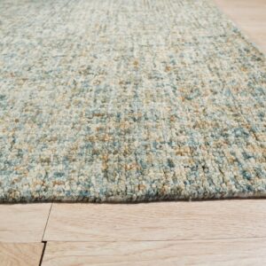 Chunky textured rug in variegated blue, cream, and tan resting on a light wood plank floor.