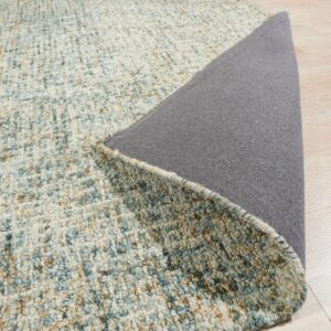 Textured blue and tan speckled rug surface is lifted, exposing the dark gray backing on light wood floors.