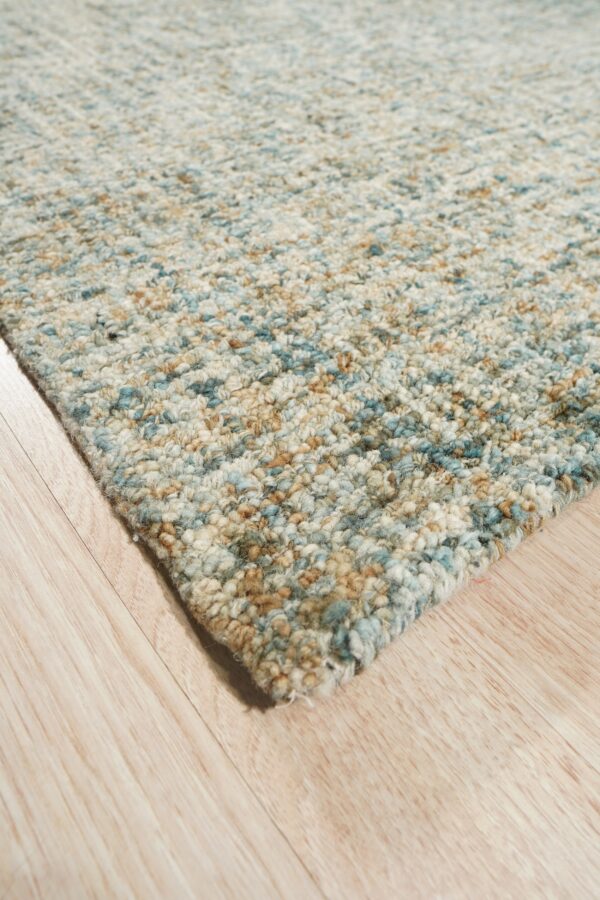 Chunky high-pile rug featuring mixed blue, tan, and cream colors on light wood plank flooring.