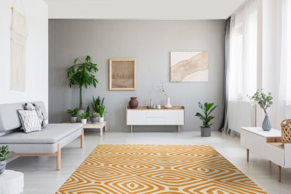 A bright orange and white geometric rug anchors a contemporary room with gray walls and wood furniture.