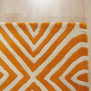 Plush orange and cream rug with a bold geometric pattern visible on light blonde wood flooring.