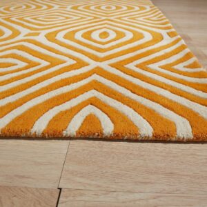 A textured orange and cream rug displays a bold geometric pattern on light wooden flooring.