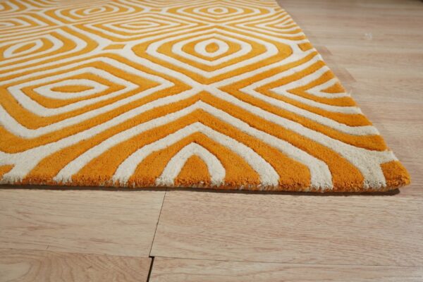 A textured orange and cream rug displays a bold geometric pattern on light wooden flooring.