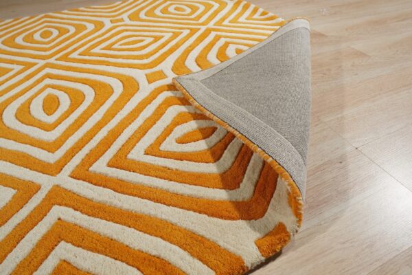 Plush orange and white rug with a sculpted geometric pattern, revealing the gray backing on light wood.