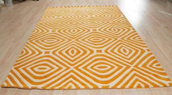 Orange and white rug with a deeply carved geometric diamond pattern sits on light wood plank flooring.