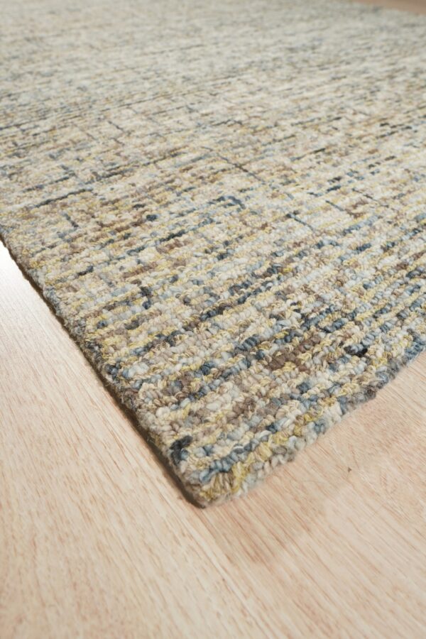 Textured loop rug featuring a subtle multicolored linear pattern in beige, blue, and yellow on light wood floors.