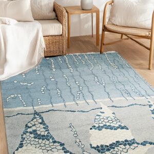 Blue, gray, and pink abstract rug anchors rattan furniture on light wood plank flooring.