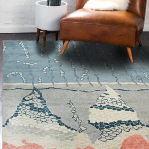 Abstract blue and gray rug with mountain patterns and a coral border under a brown leather chair.