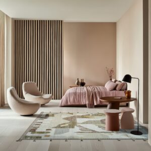 Cream rug with moss green and taupe geometric patterns anchors a minimalist bedroom with pink bedding.