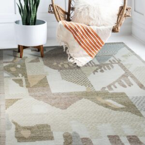 Geometric cream, tan, and olive green rug placed beneath a wicker chair and a potted snake plant.
