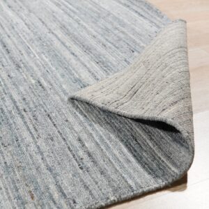 Blue and gray low-pile rug with vertical striping, partially curled back on light wood flooring.