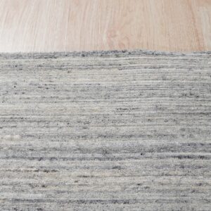 Marled gray and white rug with a horizontal textured pile rests on light blonde wood flooring.