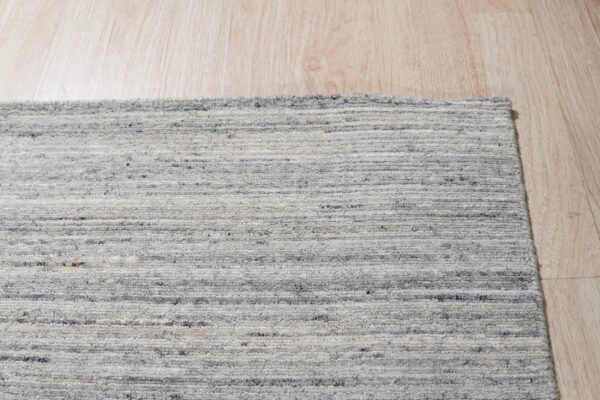 Marled gray and white rug with a horizontal textured pile rests on light blonde wood flooring.