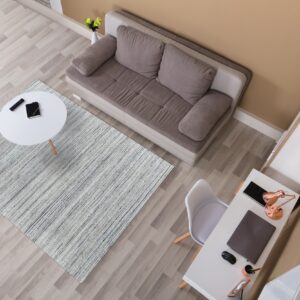 A gray and white striped rug anchors a living area with a taupe sofa and white desk on light wood floors.