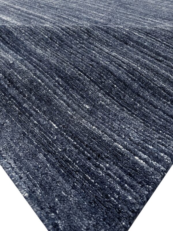 Diagonal ribs create a high-low texture across the deep navy blue and white speckled rug surface.