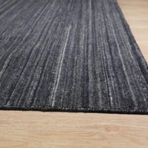 Gray textured rug with light vertical streaks covers light wood plank flooring.