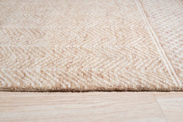 Beige and cream chevron rug detail showing high pile texture on light wood plank flooring.