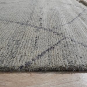 Shaggy white and gray rug featuring a dark geometric line pattern lying on light wood flooring.