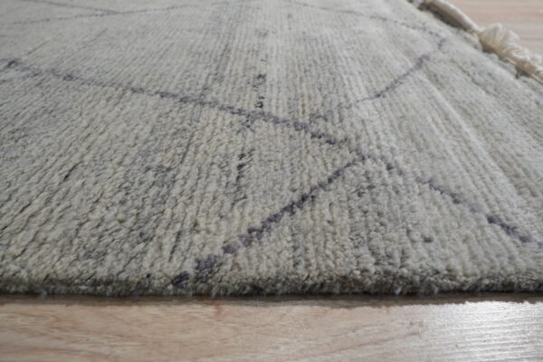 Shaggy white and gray rug featuring a dark geometric line pattern lying on light wood flooring.