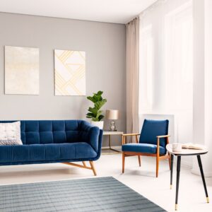 Low-pile gray and blue striped rug placed beneath a navy velvet sofa and armchair.