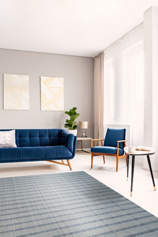 Low-pile gray and blue striped rug placed beneath a navy velvet sofa and armchair.