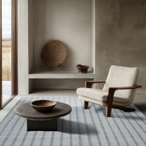 A light blue and gray striped rug anchors a minimalist room with an armchair and coffee table.
