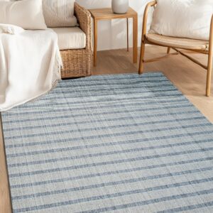 A blue and light gray low-pile striped rug is laid beneath natural wicker and wood furniture.