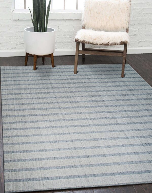 Light gray striped rug sits on dark wood floors next to a furry chair and a potted plant.