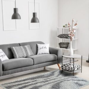 Horizontal gray and white striped rug under a charcoal sofa in a bright modern living room.
