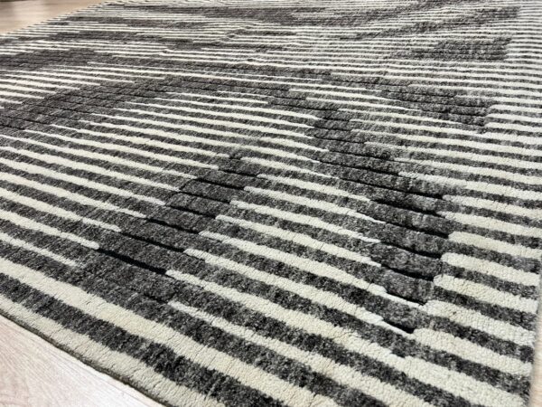 Black and cream striped shag rug with sculpted pile details lies on light wood flooring.