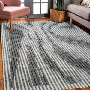 Abstract gray and white striped rug on wood flooring, next to a pink chair and a beige couch.