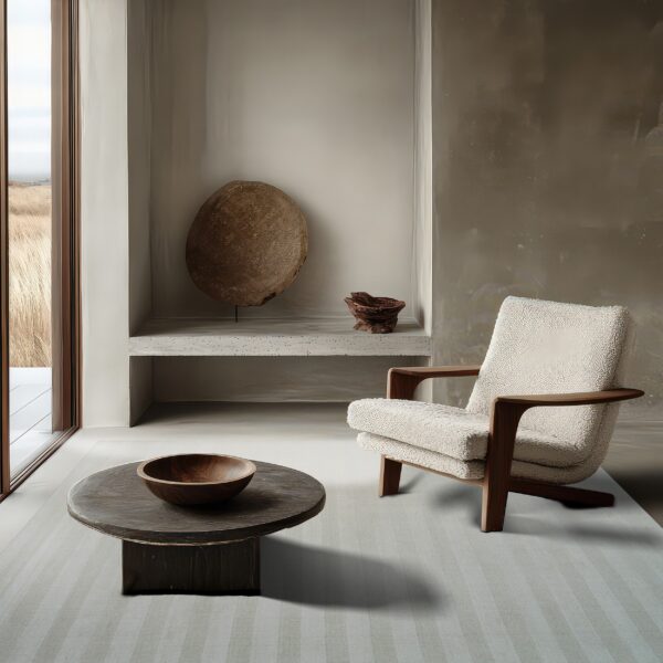 A subtly striped light gray rug grounds a neutral room furnished with a textured armchair and dark coffee table.