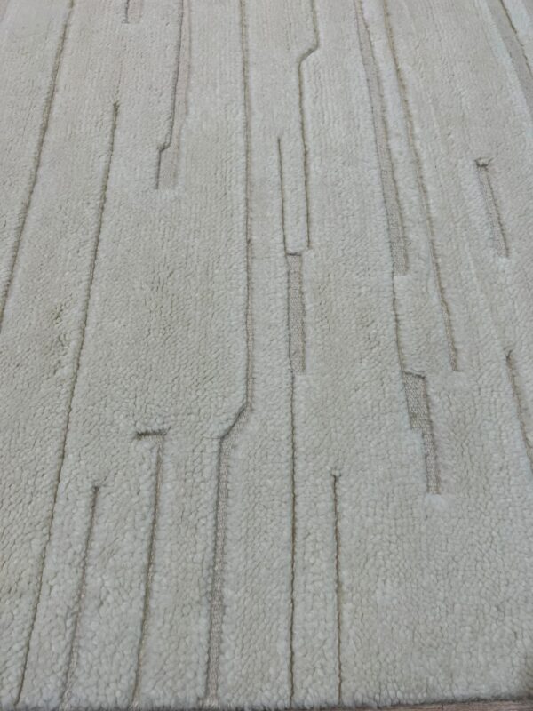 High-pile cream rug with broken vertical lines formed by flat-woven, light tan segments.