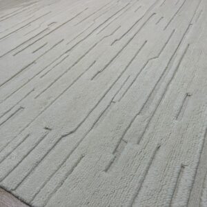 Cream high-and-low pile rug featuring deeply carved, segmented vertical lines on wood flooring.