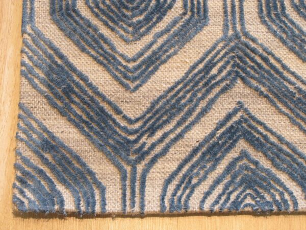 A beige rug features a raised blue textured chevron pattern on light hardwood flooring.