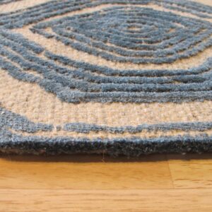 High-low pile rug with slate blue concentric diamond pattern on a natural beige field over wood flooring.