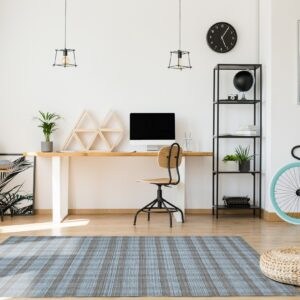 A textured blue and brown striped rug sits below a modern wood desk and office chair.