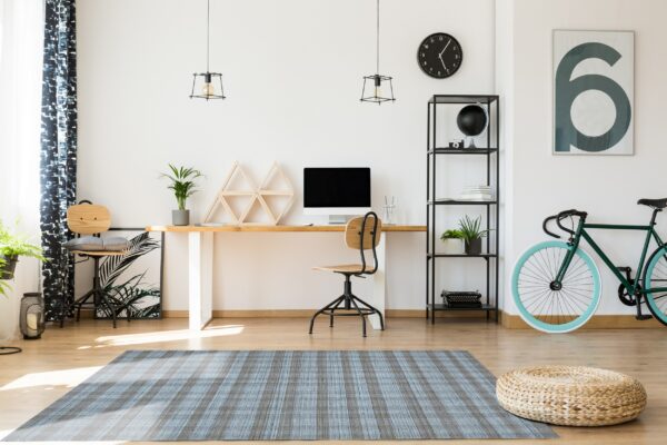 A textured blue and brown striped rug sits below a modern wood desk and office chair.