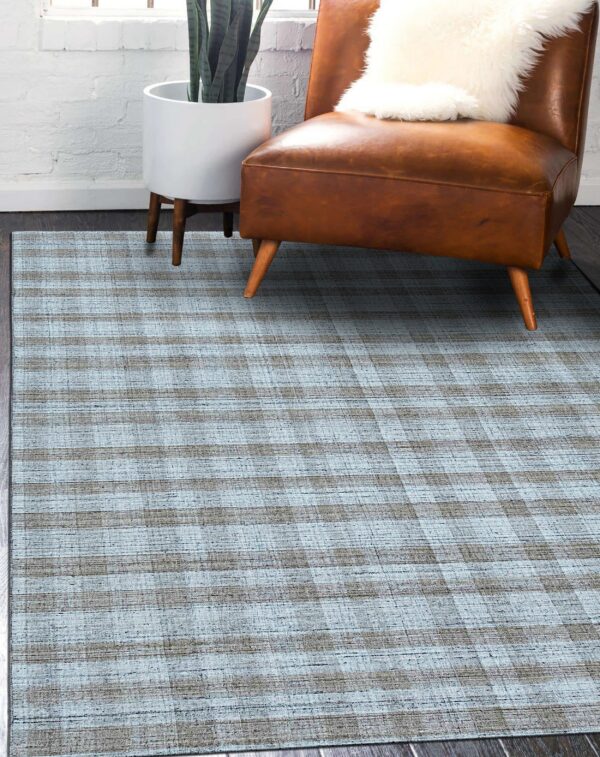 Textured blue and gray plaid rug beneath a brown leather chair on dark wood floors.