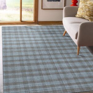 Blue and gray plaid rug rests on light tile flooring next to a beige sofa and wooden window.