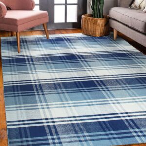 A blue, light blue, and white plaid rug lies on hardwood floors under pink and gray furniture.
