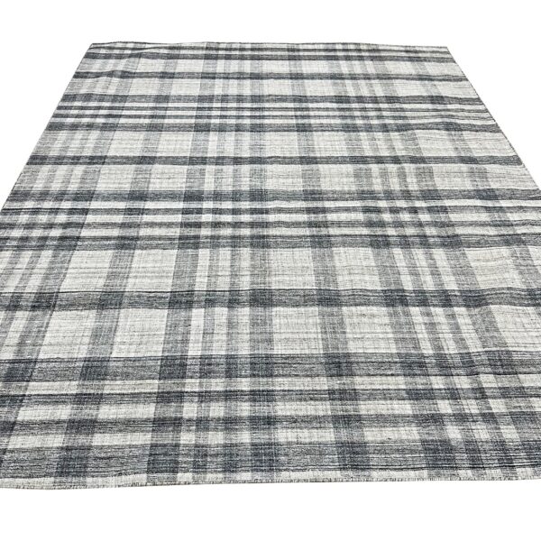 Black and white flat-woven rug featuring a visible plaid or checkered grid pattern.