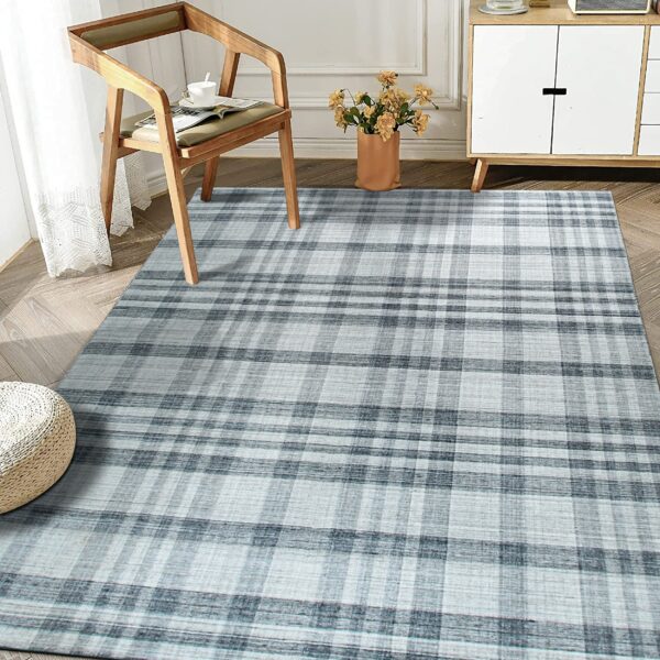 Tonal gray plaid area rug displayed on wood plank flooring beside a minimal wood chair and white cabinet.