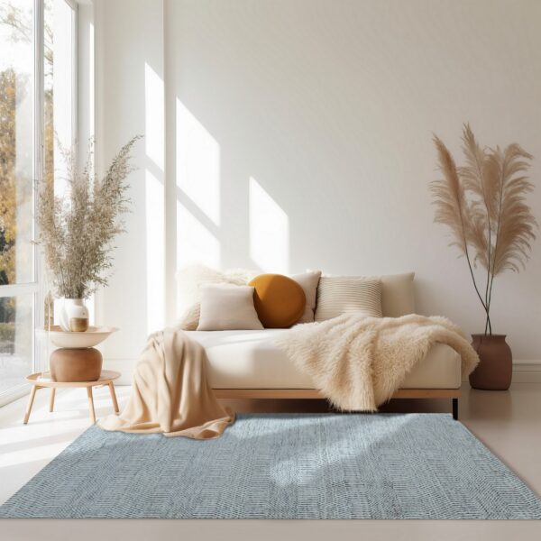Blue and white flatweave rug with a zigzag pattern under a beige sofa in a brightly sunlit room.