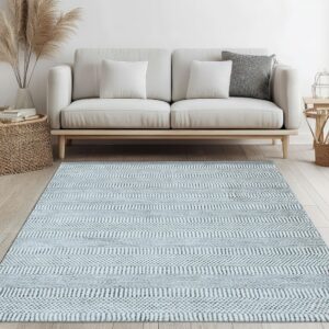 Woven light blue and gray striped rug underneath a cream sofa on light hardwood flooring.
